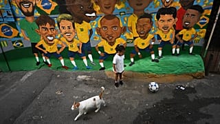 Uma criança joga futebol diante de uma imagem do "escrete" na favela Rocinha