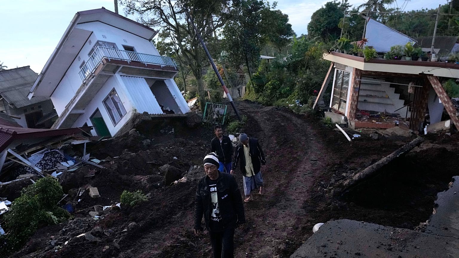 Residents walk past ruined homes damaged in Monday's earthquake in Cianjur, Indonesia. The 5.6 magnitude earthquake left hundreds dead.