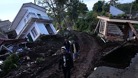 Residents walk past ruined homes damaged in Monday's earthquake in Cianjur, Indonesia. The 5.6 magnitude earthquake left hundreds dead.