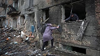 People gather their belongings from a damaged house in the town of Vyshgorod.