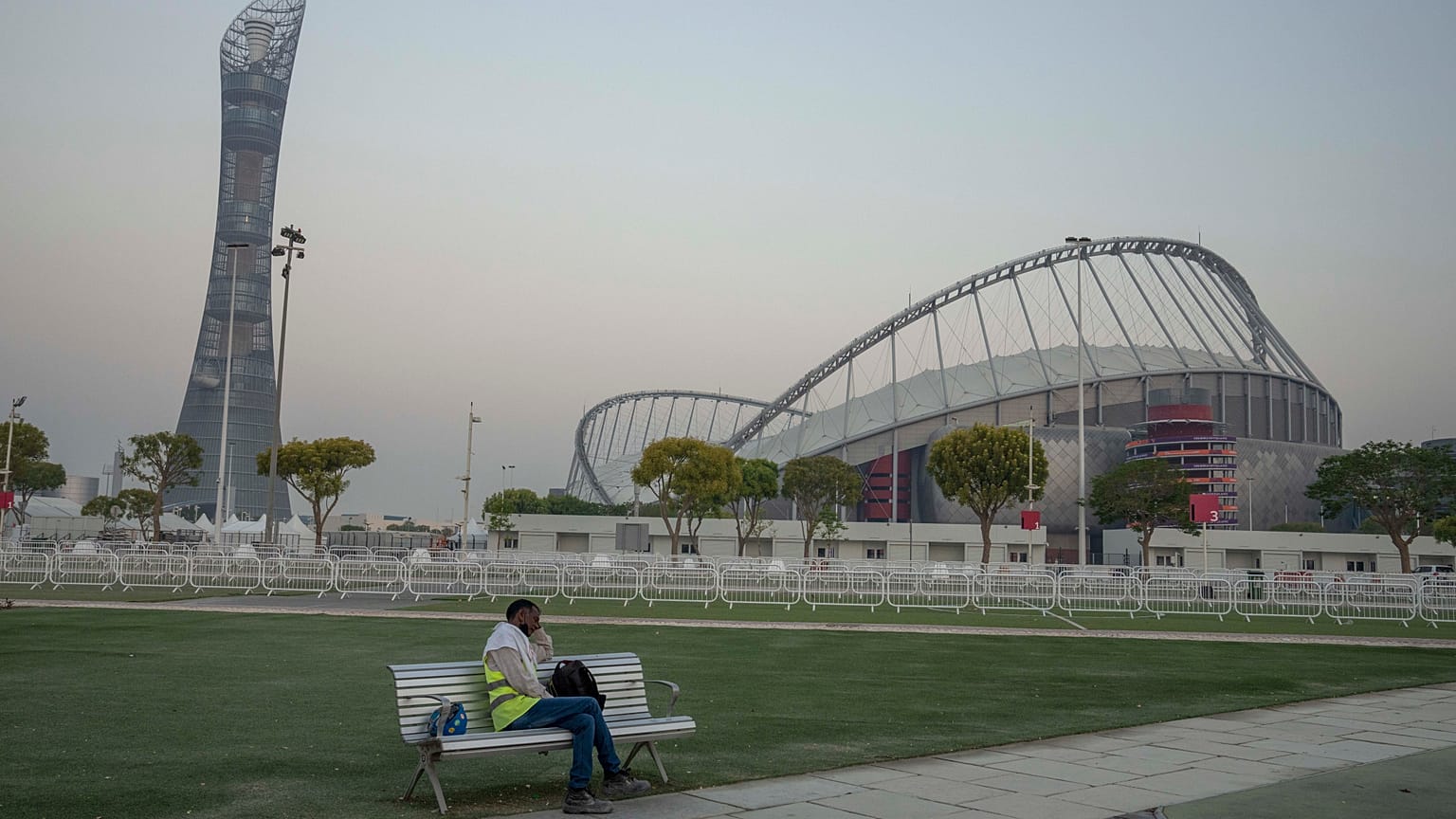 A migrant worker sleeps on a bench before his early morning shift, in front of Khalifa International Stadium in Doha, Qatar.