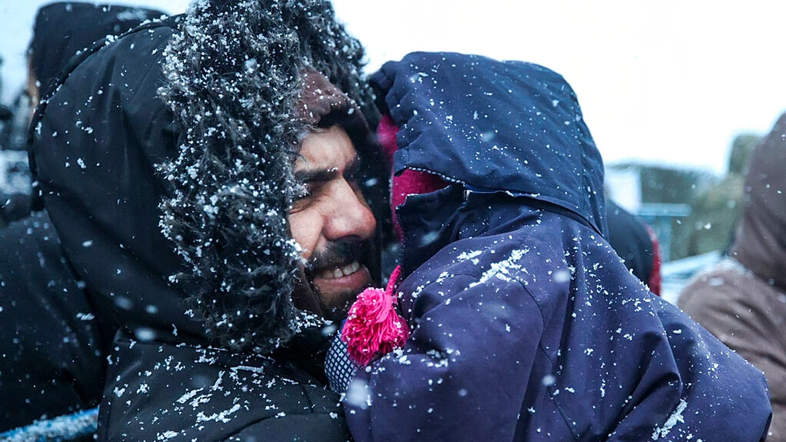 Ein Vater hält sein Kind, während er bei Schneefall vor einem Logistikzentrum am Kontrollpunkt "Kuznitsa" an der belarussisch-polnischen Grenze in der Nähe von Grodno, Belarus