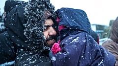 Ein Vater hält sein Kind, während er bei Schneefall vor einem Logistikzentrum am Kontrollpunkt "Kuznitsa" an der belarussisch-polnischen Grenze in der Nähe von Grodno, Belarus
