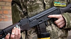An armed civil defence woman holds a Kalashnikov assault rifle while patrolling an empty street due to a curfew in Kyiv, 27 February 2022
