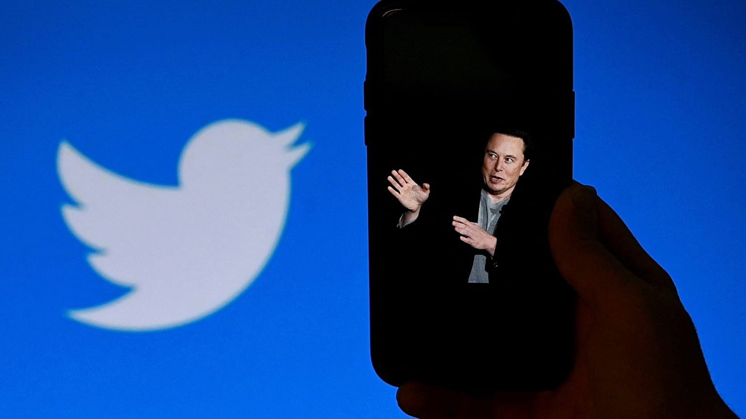 In this file photo taken on October 4, 2022, a phone screen displays a photo of Elon Musk with the Twitter logo shown in the background, 