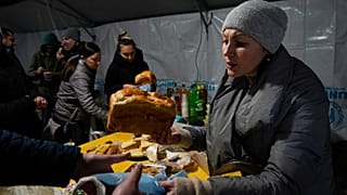 A volunteer gives a free meal to people who lost power after a recent Russian rocket attack on a heating point in Vyshhorod, north of Kyiv, Ukraine, Friday, Nov. 25, 2022.