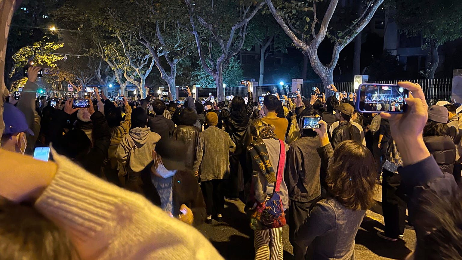 Residents record the scene as they mourn for the victims a recent deadly fire at a residential building in Urumqi city and calls for press freedom in Shanghai, Nov. 26, 2022.