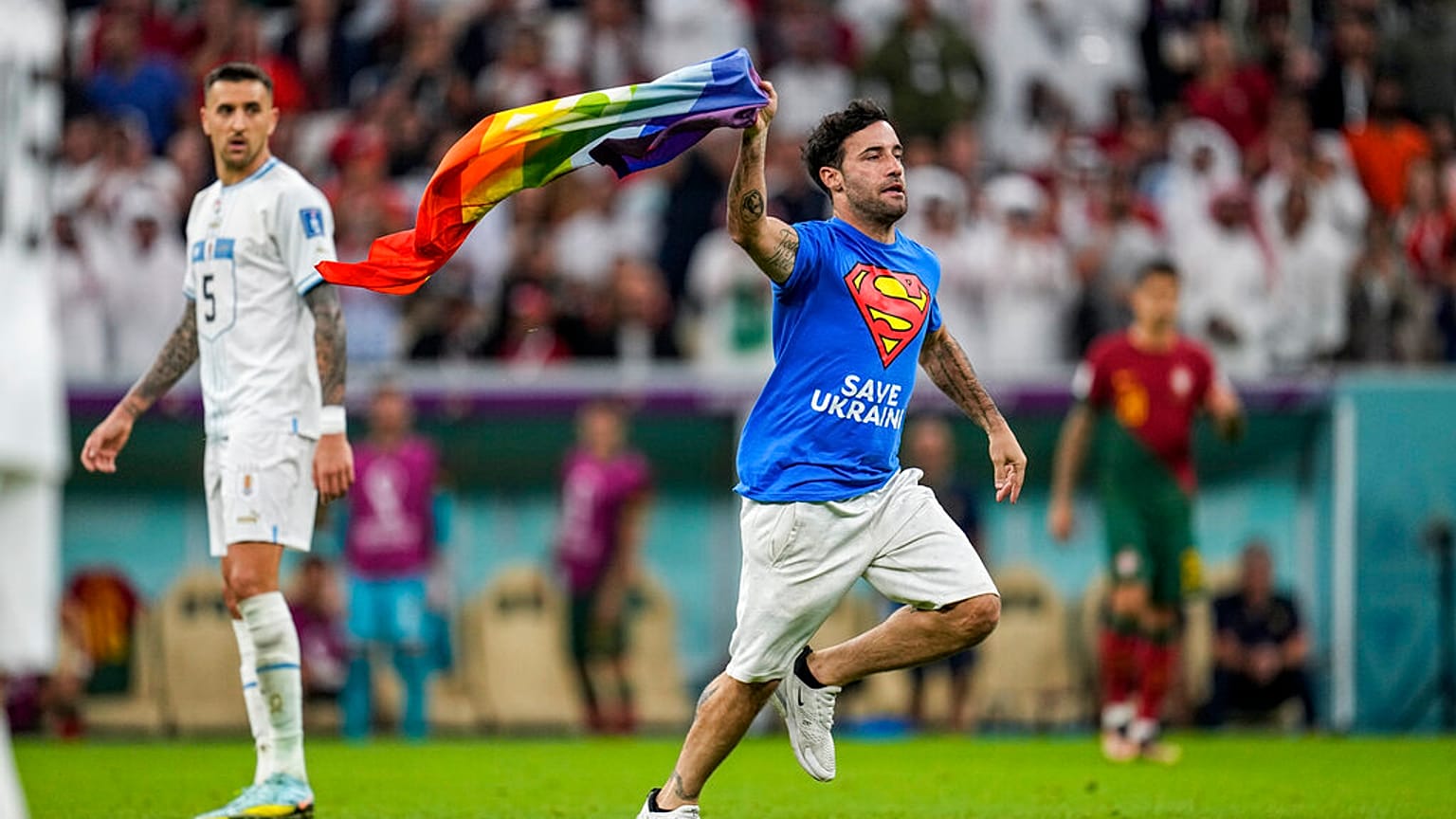 A pitch invader runs across the field with a rainbow flag during the World Cup match between Portugal and Uruguay, at the Lusail Stadium in Lusail, Qatar, 28 October.