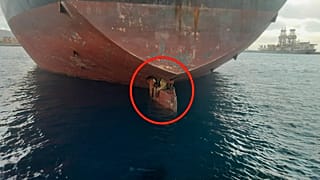 The migrants are pictured on the rudder of the ship