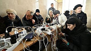 Des habitants de Kherson rechargent leur téléphone à la gare de la ville, l'un des rares bâtiments à disposer de l'électricité.