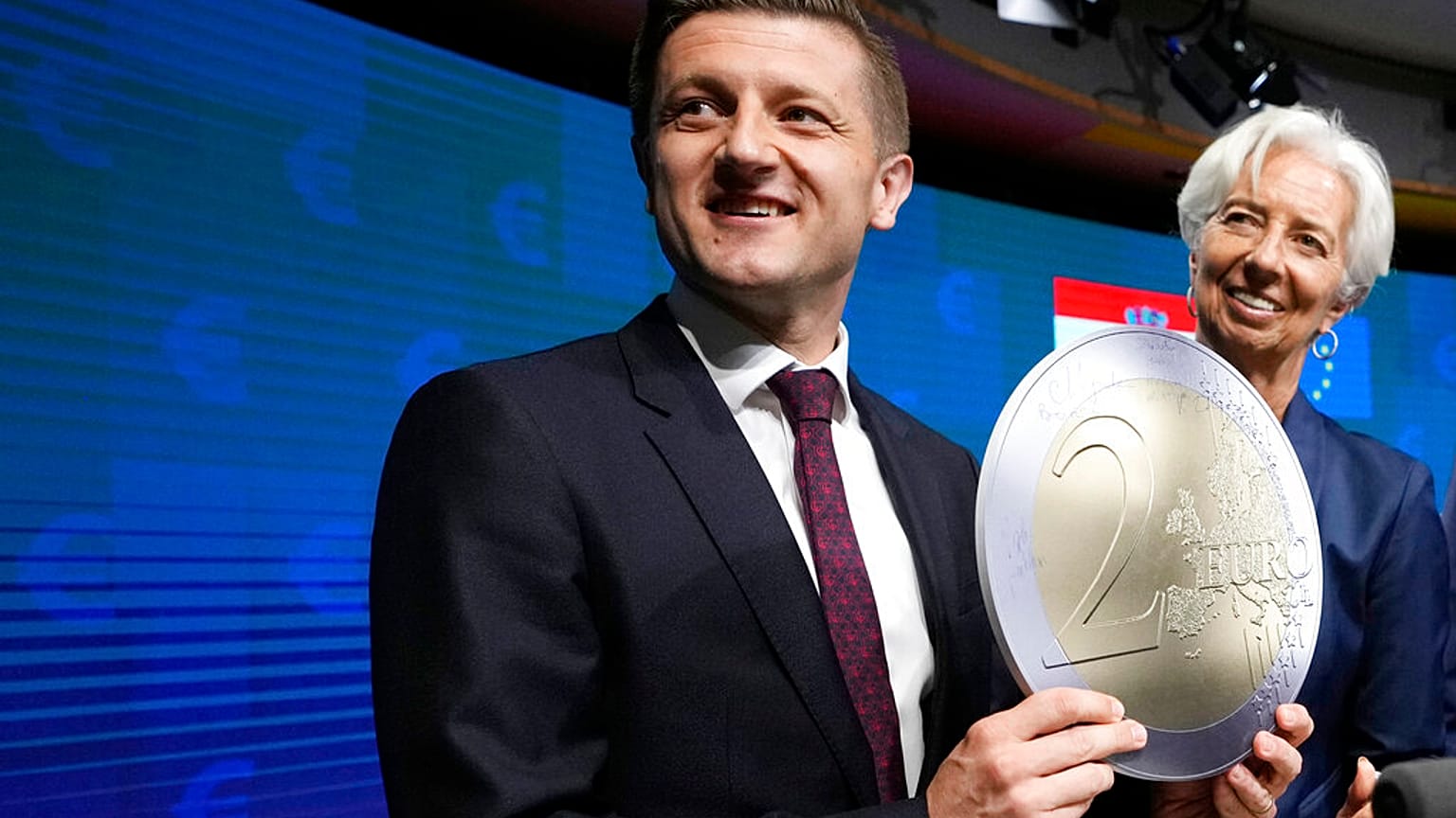 Croatia's ex-Finance Minister Zdravko Maric holds up a cardboard euro coin after a signing ceremony for Croatia to join the euro in Brussels, Tuesday, July 12, 2022.