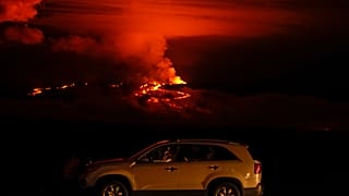 Un hombre habla por teléfono en su coche junto a Saddle Road mientras el volcán Mauna Loa entra en erupción el miércoles 30 de noviembre de 2022, cerca de Hilo, Hawái.