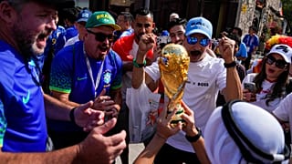 Soccer fans cheer as a man hoists a replica of the World Cup trophy at the Souq Waqif, in Doha, Nov. 23, 2022.