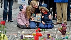 A woman and children sit and mourn for the victims of the bombings at the Place de la Bourse in the center of Brussels, Wednesday, March 23, 2016