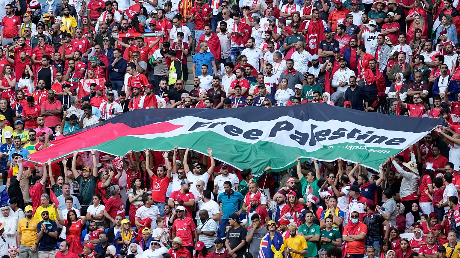مشجعون يرفعون علمًا كتب عليه "فلسطين حرة" خلال مباراة كأس العالم بين تونس وأستراليا في الدوحة. 
