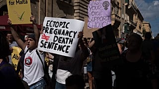 Protesters carry placards and walk through Valletta's streets during an abortion rights rally on September 25, 2022 in Valletta, Malta.