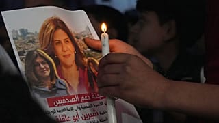 A Palestinian holds a light candle and a picture of slain Al Jazeera journalist Shireen Abu Akleh.