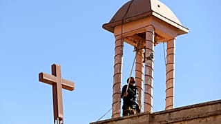 Un combattant kurde irakien fait sonner la cloche d'une église, endommagée par Daesh pendant leur occupation de Bashiqa, à l'est de Mossoul, en Irak, mercredi 7 décembre 2016.