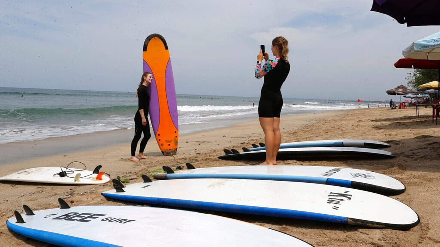 A tourists has her photo taken with a surfboard on a beach in Bali, Indonesia.