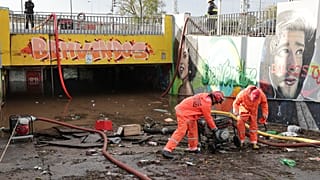 Elementos dos bombeiros usam bombas de escoamento de águas no acesso pedonal inferior à estação de comboios de Algés