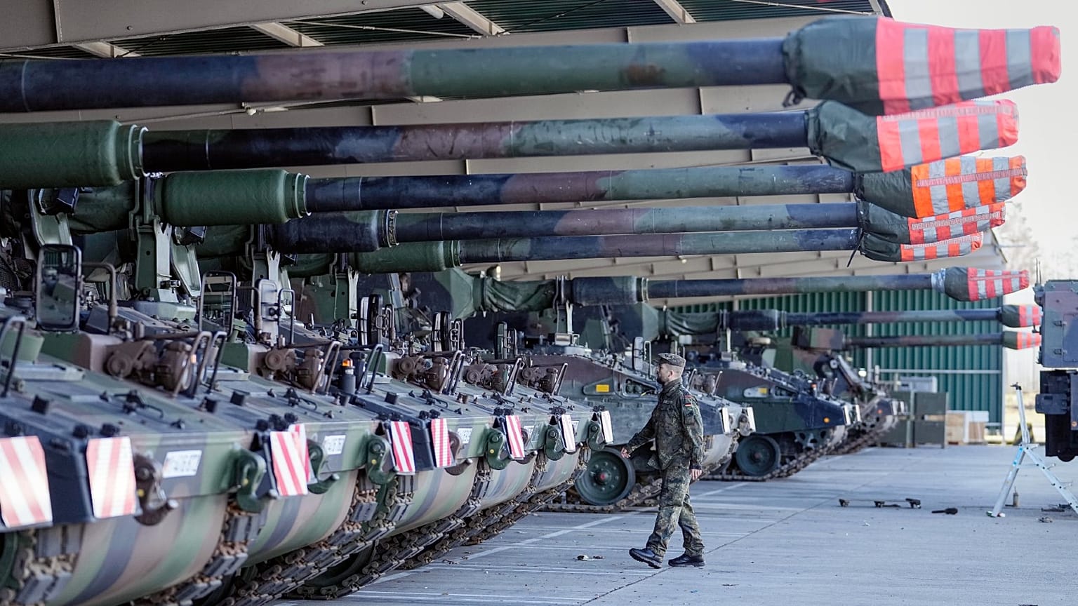 German soldiers walk beside tank howitzers 2000 prior to transportation to Lithuania at the Bundeswehr army base in Munster, northern Germany, Feb. 14, 2022. 