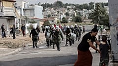 Riot police walk during a raid in a Roma settlement in Aspropyrgos.
