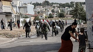 Riot police walk during a raid in a Roma settlement in Aspropyrgos.