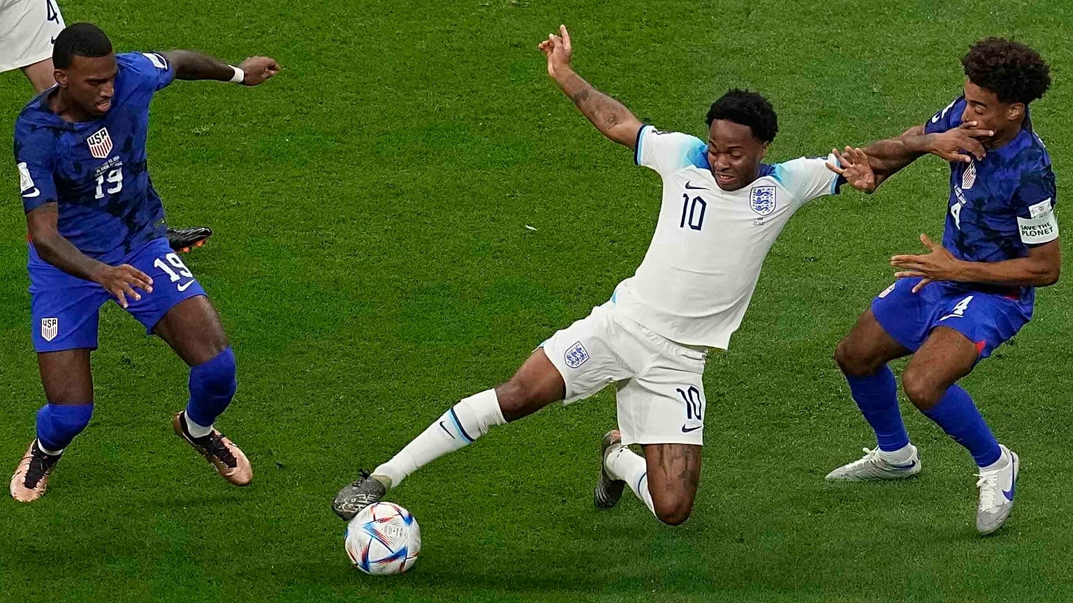 Raheem Sterling (középen) az amerikai Haji Wright (balra) és Tyler Adams között az Anglia-Egyesült Államok mérkőzésen az al-hori al-Bajt Stadionban 2022. november 25-én.
