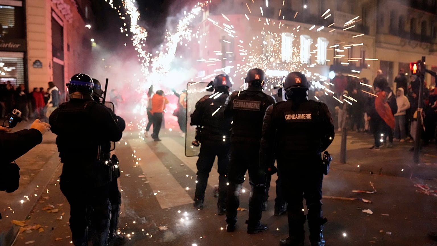 Gendarmes franceses rodeados de fuegos artificiales tras el partido de Marruecos en cuartos de final, en la avenida de los Campos Elíseos, en París, el 10 de diciembre de 2022