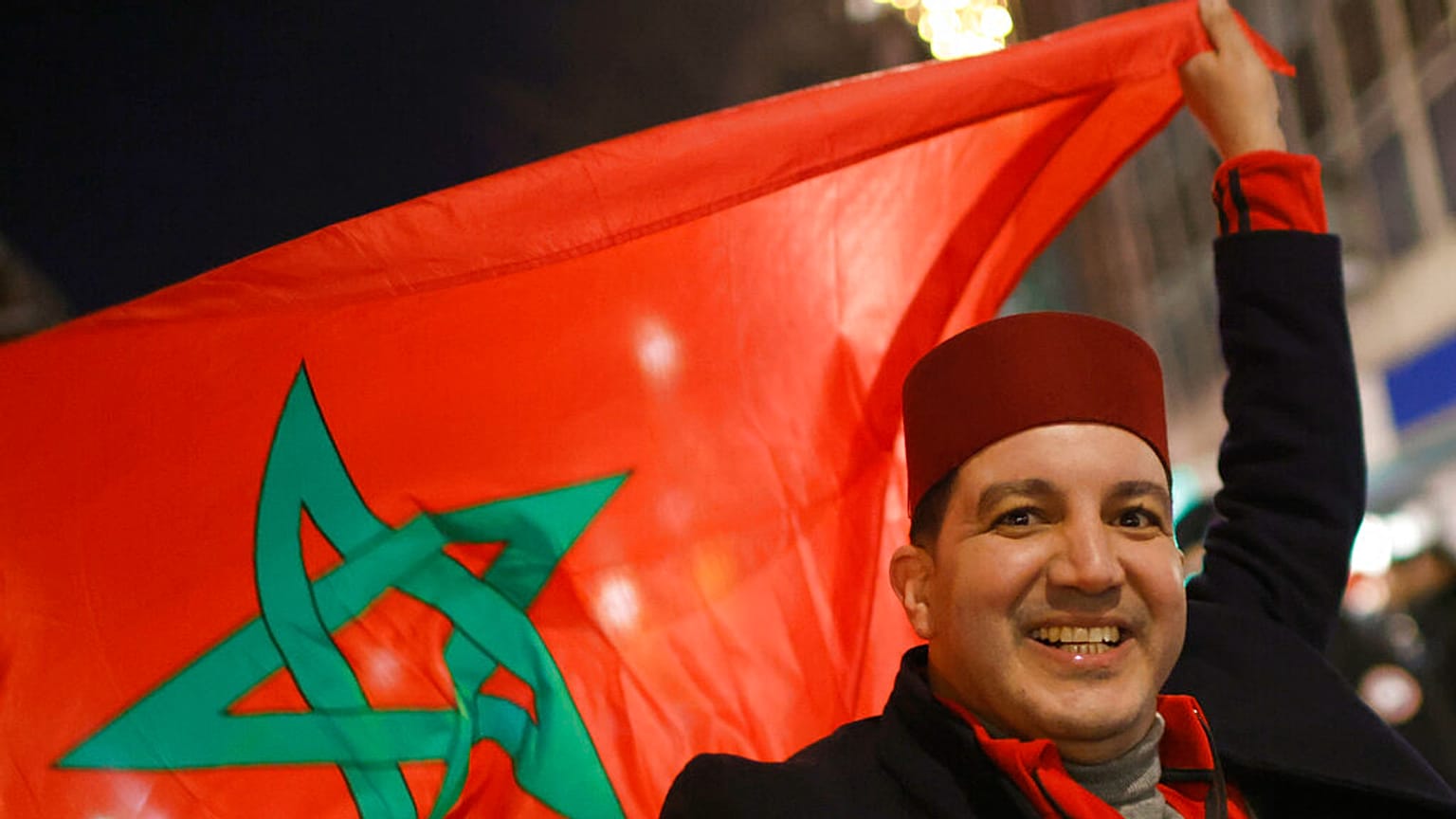 Un supporter marocain célèbre la victoire de son équipe en brandissant le drapeau du Maroc, 10 décembre 2022