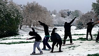 Young people slide over the snow on skateboards