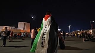 Fußballfan mit Flagge, auf der "Freiheit für Palästina" gefordert wird