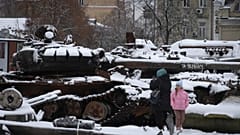 Frau und ein Kind vor beschädigten russischen Militärfahrzeugen im Zentrum von Kiew