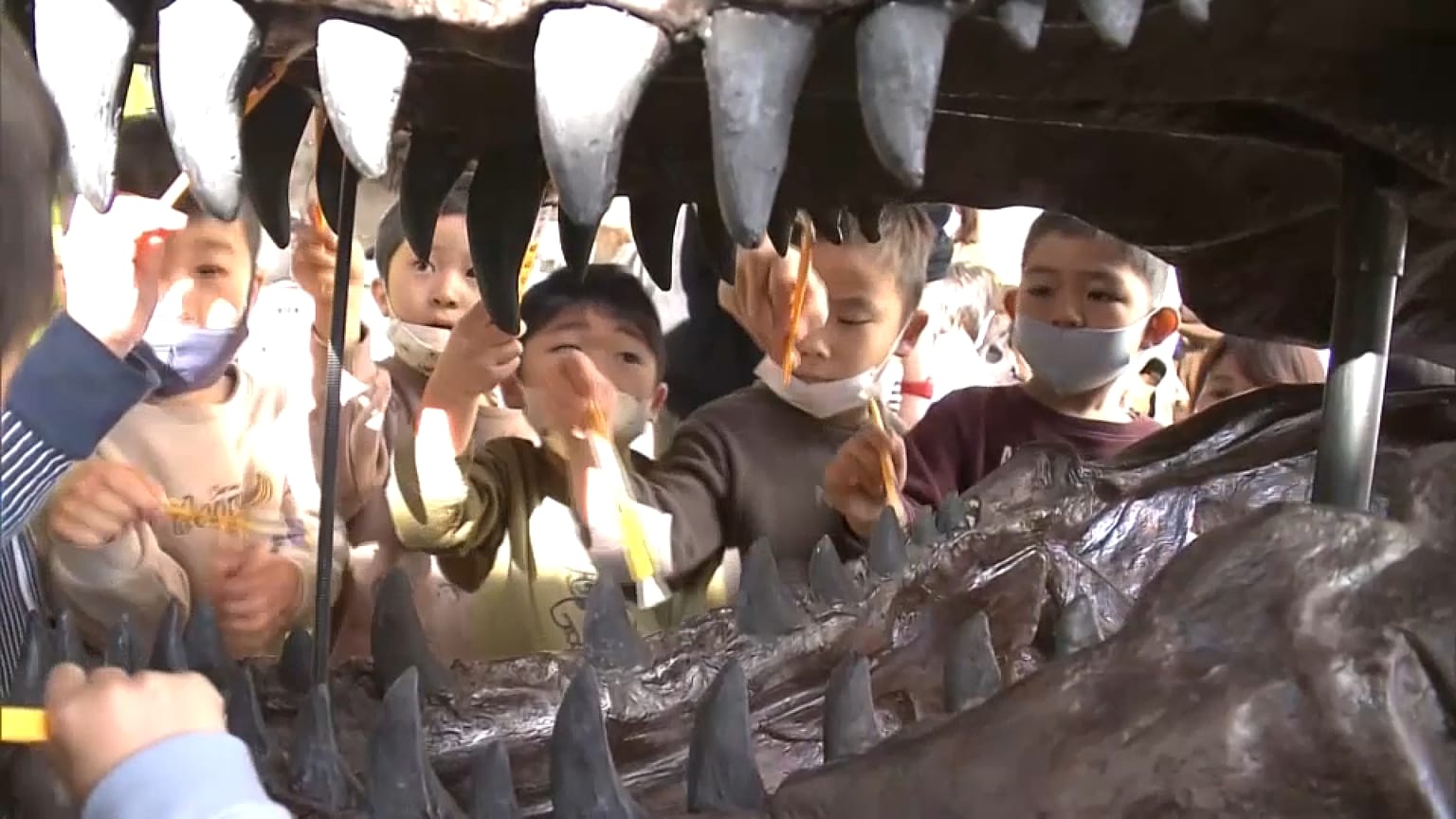 Crianças limpam os dentes a um esqueleto de dinossauro