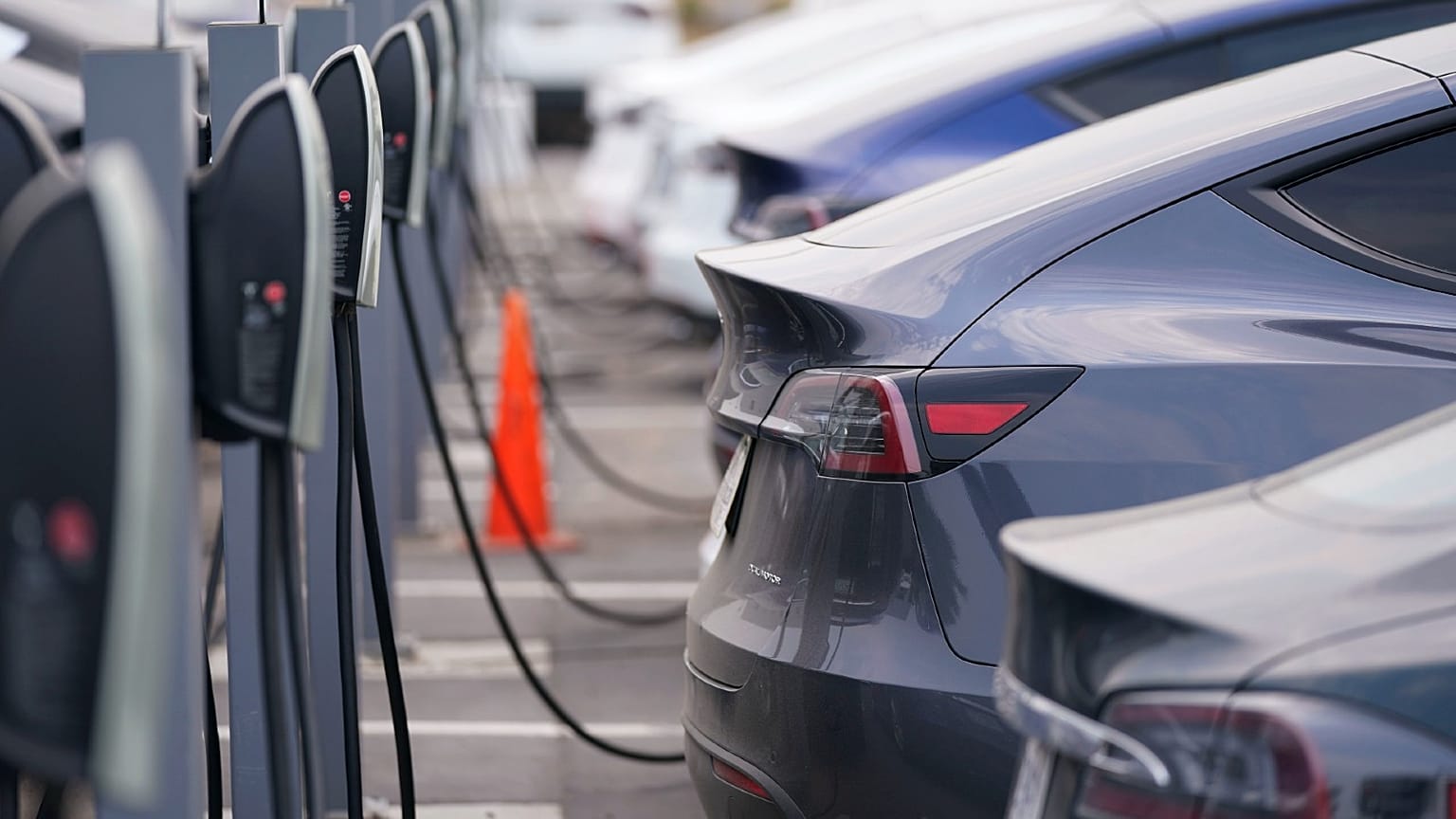 This Aug. 23, 2020 photo shows a long line of unsold 2020 models charge outside a Tesla dealership in Littleton, Colo. 