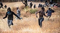 Migrants run on Spanish soil after crossing the fences separating the Spanish enclave of Melilla from Morocco in Melilla, Spain