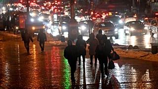Local residents walk past cars stuck in a traffic jam as the Kyiv metro network remains out of service on December 16 2022,
