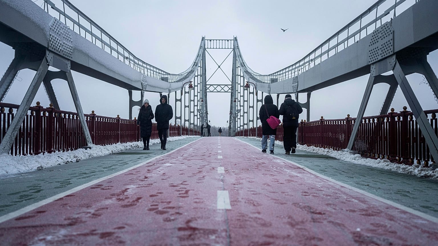 People walk on pedestrian bridge across the Dnipro river in Kyiv, Ukraine, Thursday, Dec. 15, 2022.