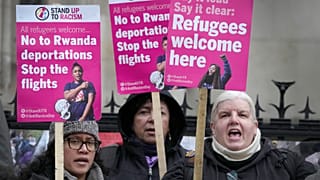 Stand Up To Racism campaigners hold banners outside the High Court in London, Monday, Dec. 19, 2022.
