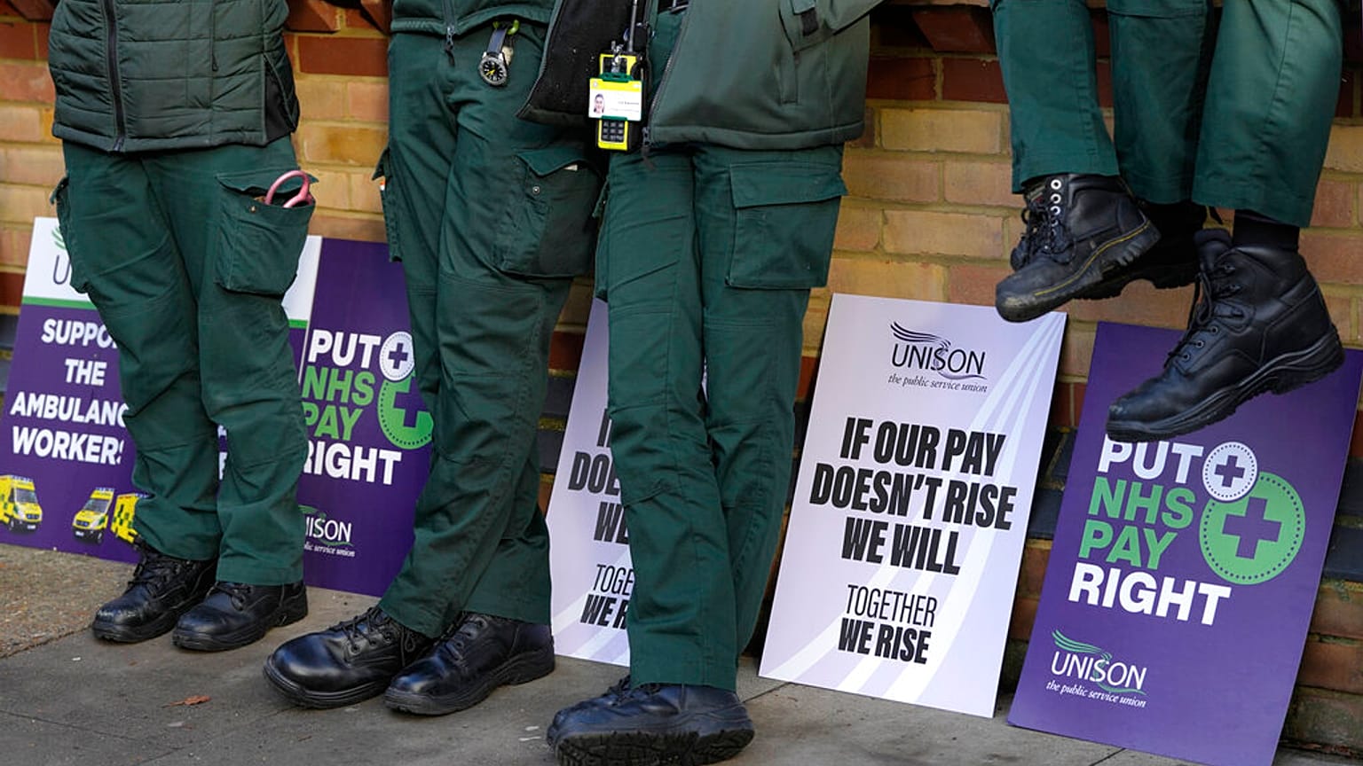 Placards lean against a wall alongside ambulance workers on a picket line in London, Wednesday, Dec. 21, 2022