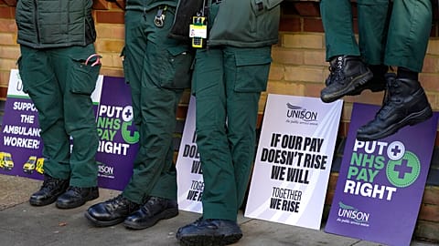 Placards lean against a wall alongside ambulance workers on a picket line in London, Wednesday, Dec. 21, 2022