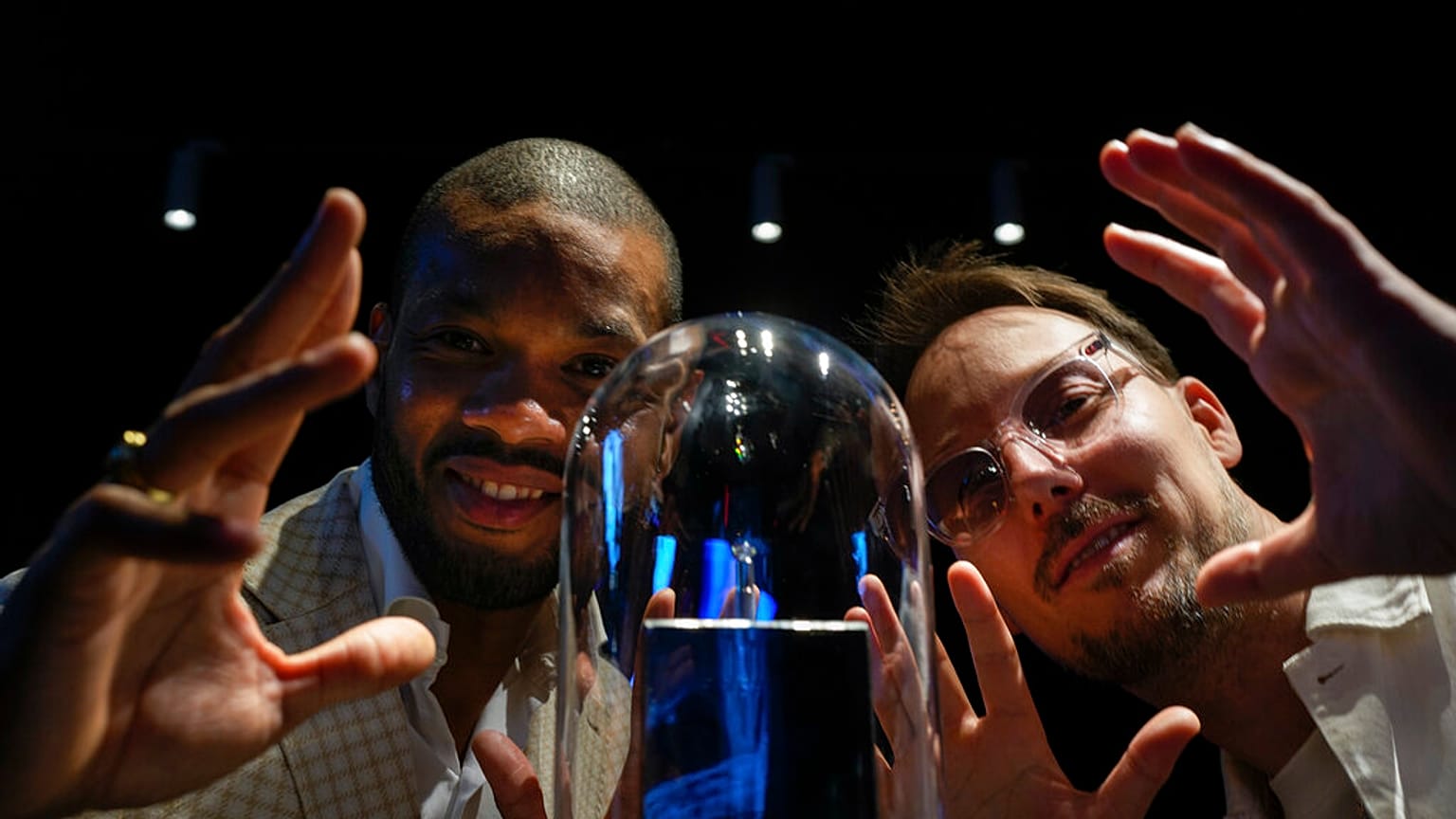Calvin Jong-A-Pin, sales and marketing specialist at Gassan Diamonds, left, and artist Pablo Lücker, right, pose with the smallest work of art on a diamond, an engraved heart.