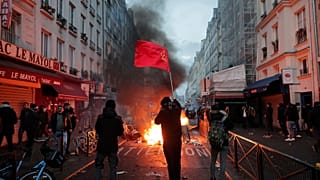 members of Kurdish community waves the Kurdish communist flags next to a barricade on fire at the crime scene where a shooting took place in Paris, Friday, Dec. 23, 2022. 