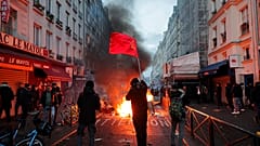 Ein Mitglied der kurdischen Gemeinschaft schwenkt die Fahnen der kurdischen Kommunisten neben einer brennenden Barrikade am Tatort einer Schießerei in Paris