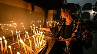 A woman lights candles inside the Church of the Nativity, traditionally believed to be the birthplace of Jesus Christ, in the West Bank town of Bethlehem,Saturday , Dec. 24, 2