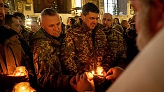 Украинские военнослужащие получают Вифлеемский огонь во время рождественской службы в Харькове, 25 декабря 2022 года.