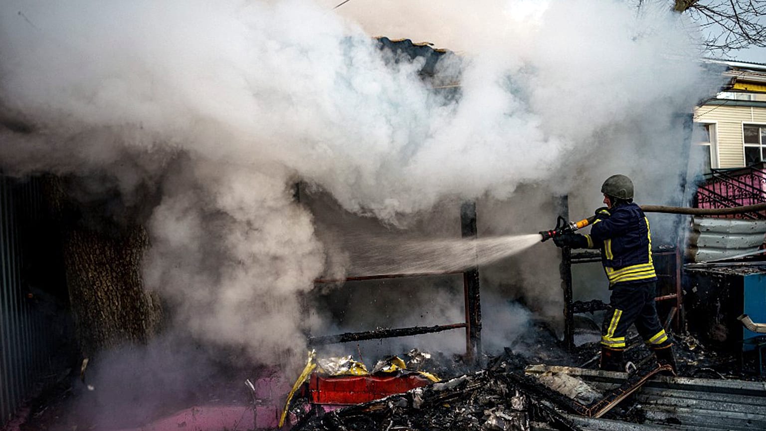 A rescuer extinguishes a fire in a burning shop after Russian shelling to Ukrainian city of Kherson, 24 December 2022