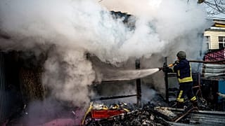 A rescuer extinguishes a fire in a burning shop after Russian shelling to Ukrainian city of Kherson, 24 December 2022