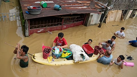 Des habitants donnent des oignons et d'autres aliments le long d'une route inondée par le typhon Noru dans la ville de San Miguel, Philippines