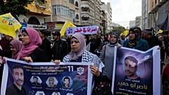  فلسطينيون يحملون ملصقات لناصر أبو حميد، أسير فلسطيني توفي بسرطان الرئة في الحجز الإسرائيلي الأسبوع الماضي، في مدينة غزة، 27 ديسمبر 2022.